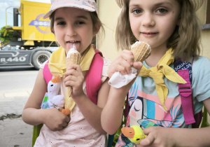 dwie dziewczynki siedzą i jedzą lody