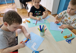 Dziec iprzy stoliku siedzą i koloruja kalosze
