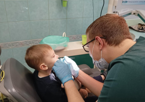 Stomatolog zagląda w jamę ustną chłopcu