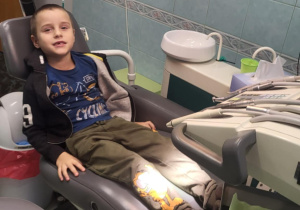 Chłopiec siedzi na fotelu dentystycznym