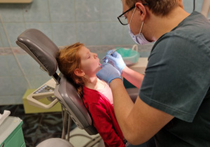 Dziewczynka na fotelu stomatologicznym ma badanie zęby