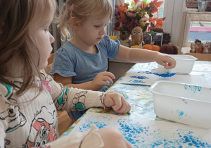 Dziewczynki przy stoliku odciskują folię bąbelkową