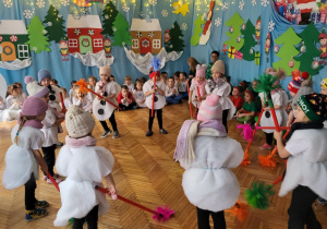 Dzieci udają, że sprzatają miotelkami śnieg