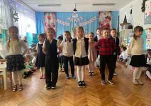 Dzieci z grupy czwartej stoją w rzędach i szykują się do piosenki