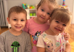 Dwie dziewczynki z chłopcem pozują do zdjęcia