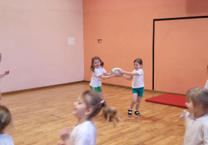 Dwie dziewczynki podają sobie piłkę