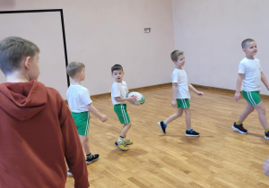 Chłopiecpodaje piłke swojemu koledze stojącemu za jego plecami