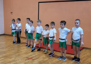 Chłopcy z szarfami u pasa stoją pod ścianą