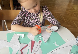 Dziewczynka wycina nożyczkami głowę bociana