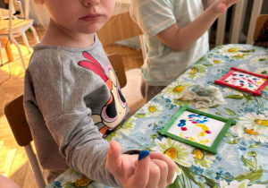 Dziewczynka nabiera na palec niebieską farbę