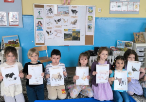 Dzieci pokazują ilustracje zwierząt wiejskich