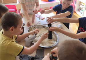 Dzieci nabierają ryż i wsypuja do skarpet