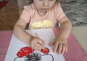 Dziewczynka stempluje kwieatek na czerwono