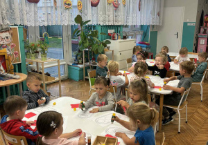 Dzieci siedzą przy stolikach