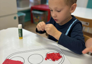 Chłopiec drze papier na drobne kawałki