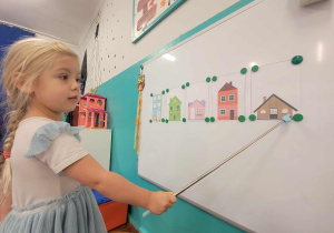Dziewczynka wskazuje brązowy najmniejszy domek