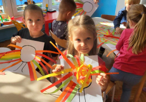 dzieci przyklejają kolorowe paski w kolorach jesiennych na szblon korony jesiennego drzewa