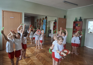 Dzieci podają sobie nad głowami koła