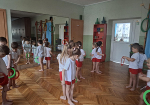 Dzieci stoją plecami do siebie i podają sobie koła bokiem