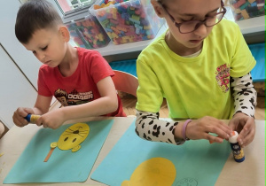 Dzieci przy stoliku przykelejają paski