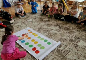 Dzieci siedzą przed ilustrowaną partyturą