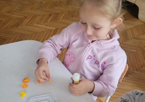 Dziewczynka przykleja pomarańczowe kulki
