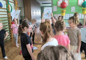 Dzieci stoją na środku sali gimnastycznej
