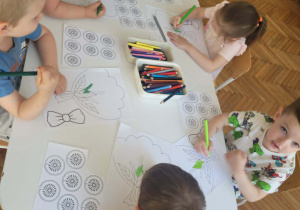 Dzieci przy stoliku kolorują łodygę i liście