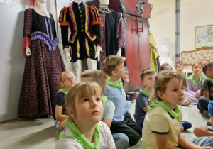 Dzieci siedzą w sali kostiumowej