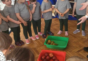 dzieci segregują owoce jabłka, gruszki i banany do odpowiednich pojemników: czerwony, zielony i żółty