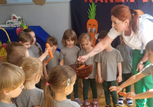 dzieci wyrywaja z grządek marchewki i chowają je do koszyka