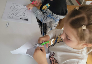 Dzieci przy stole wycinają samolot