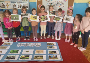 dziewczynki prezentują ilustracje łąkowych zwierząt