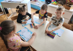 Dzieci przy stoliku malują mazakami