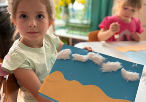 Dziewczynka pokazuje obrazek plaży z chmurami