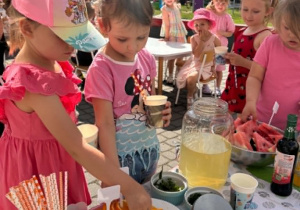 Dziewczynki wkładają do lemoniady pomarańczę