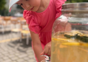 Dziewczynka ze słoika nalewa sobie lemoniady