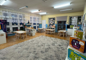 sala przedszkolna z dywanem stolikami i meblami
