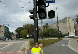 Dwie dziewczynki stoją przy sygnalizatorze świetlnym