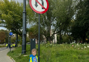 Chłopiec stoi obok znaku drogowego