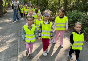 Grupa dzieci idzie w kamizelkach odblaskowych