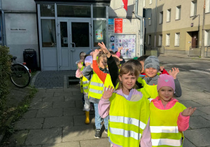 Dzieci stoją w kamizelkach odblaskowych