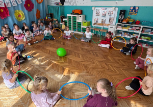 Dzieci siedzą w kole z obręczami