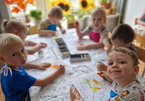 dzieci przy stoliku kolorują jesienne liście