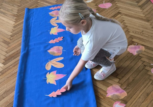 Dziewczynka układa liście na materiale