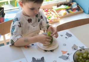 chłopiec wykonuje jeża z owoców