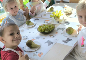 dzieci siedzą przy stoliku i uśmiechają się