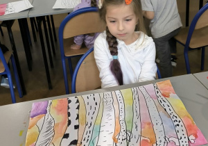 dziewczynka ma przed sobą pracę z drzewami kolorowymi