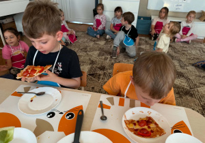 chłopiec trzyma kawałek pizzy