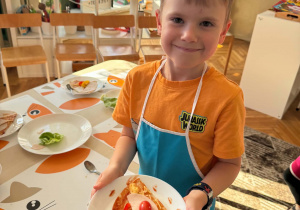 chłopiec trzyma talerz z kawałkiem pizzy